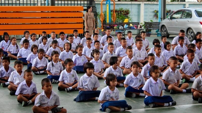 Jeunes élèves thaïlandais assis en rangs lors d'une activité scolaire.