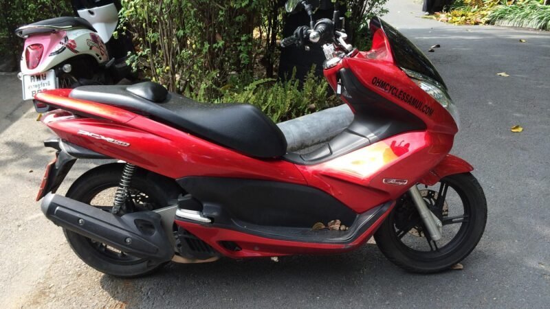 Scooter rouge stationné sur la route en Thaïlande.