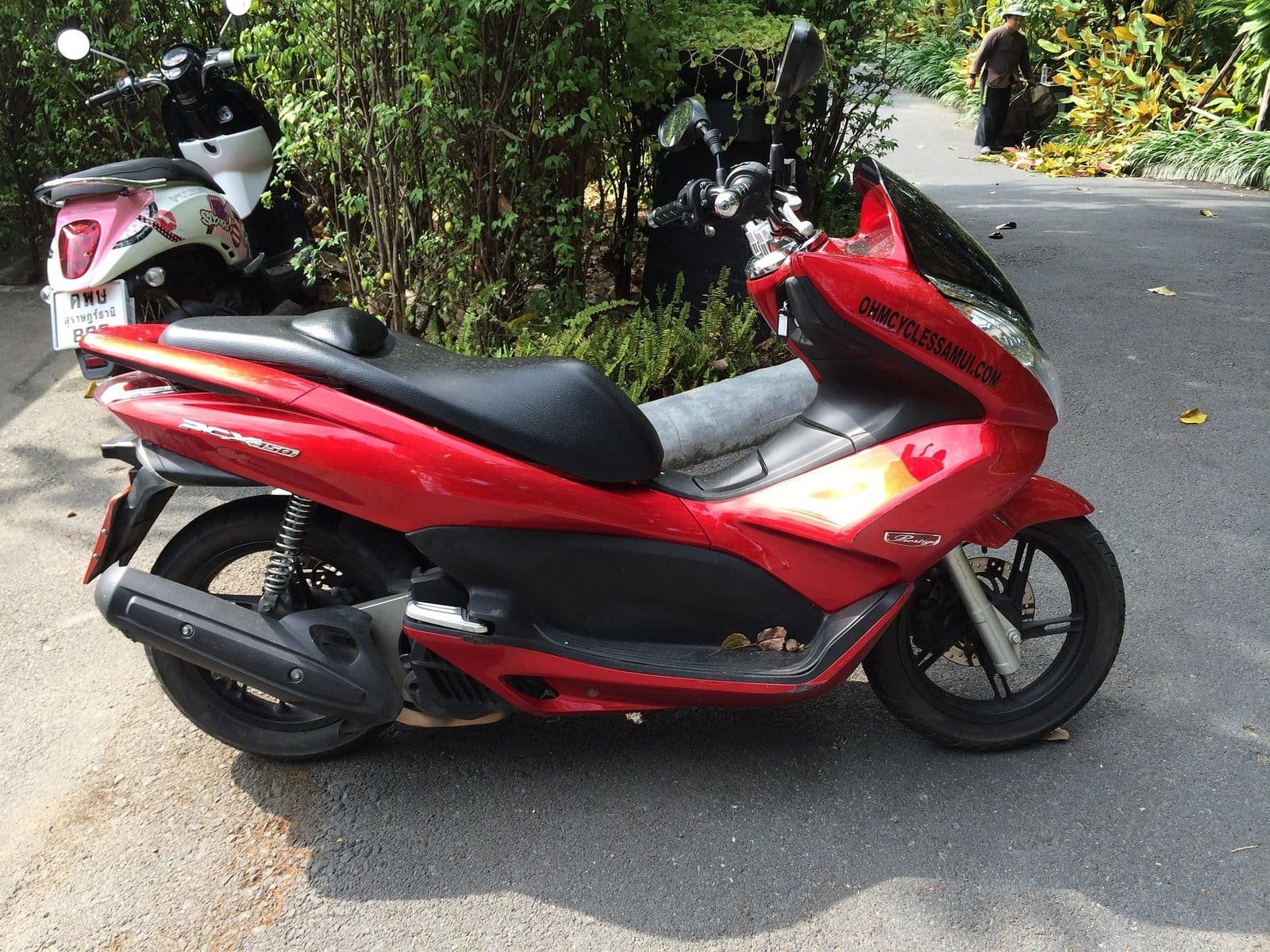 Scooter rouge stationné sur la route en Thaïlande.
