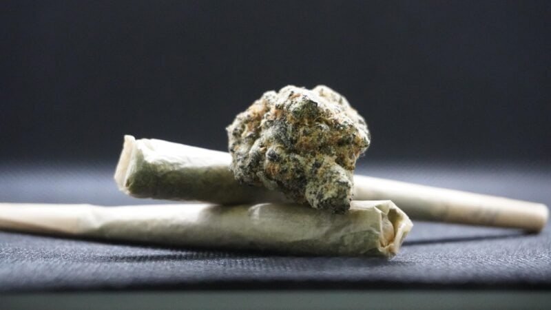 Cannabis en Thaïlande, plante et joint sur fond noir.