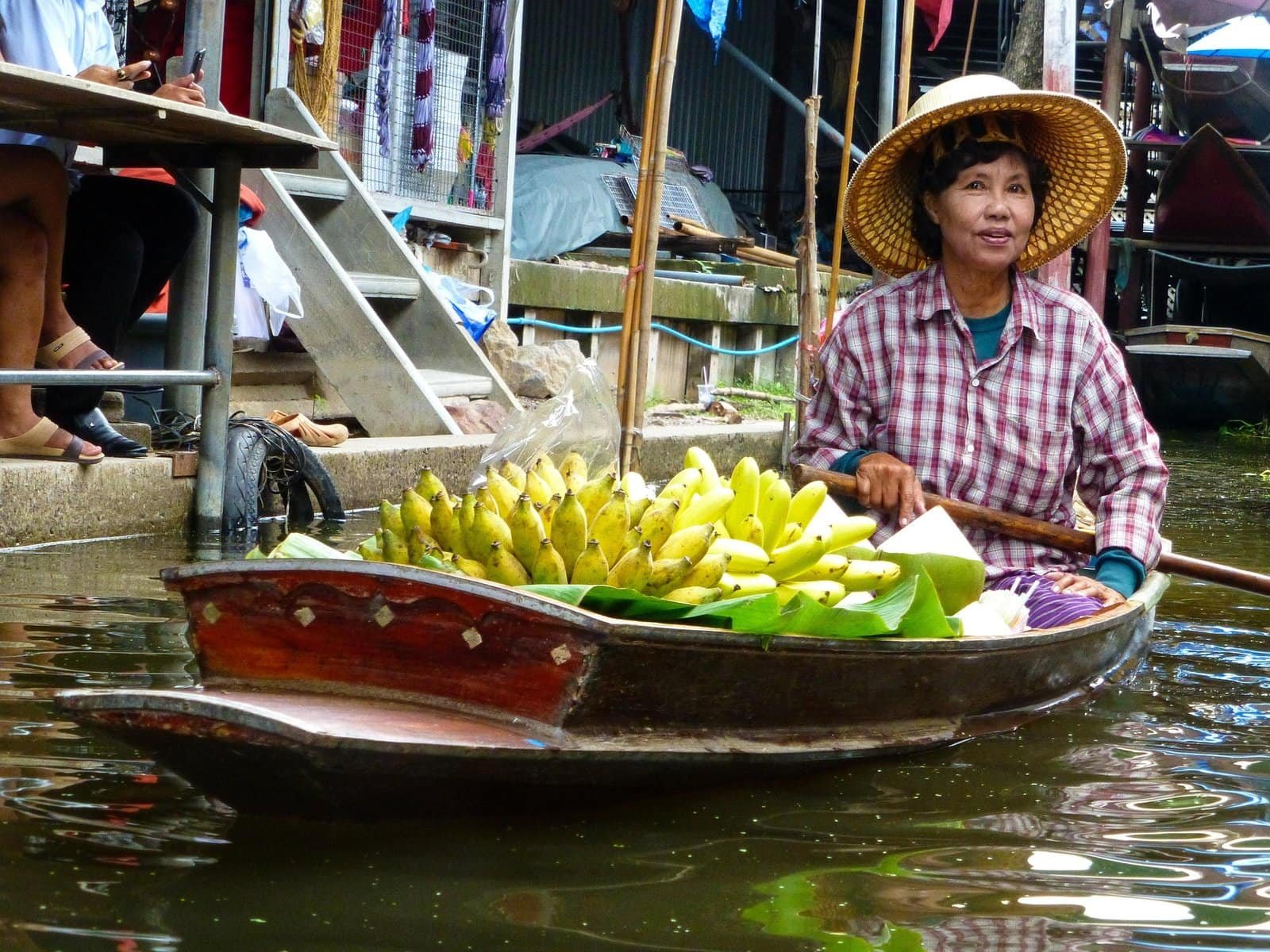 Femme sur un bateau de marché flottant avec des bananes en Thaïlande.