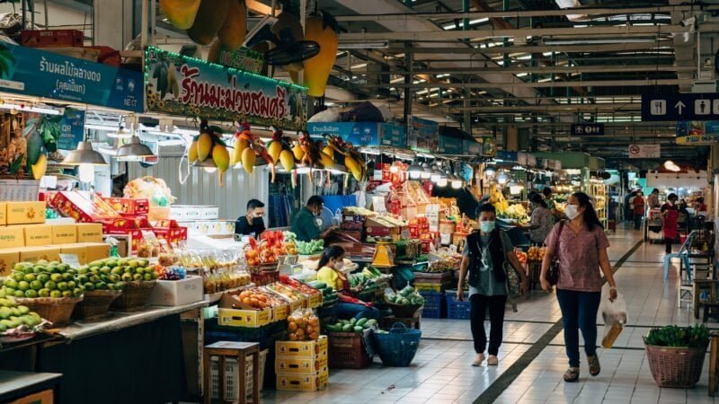 Marché intérieur animé à Bangkok avec fruits et légumes frais.