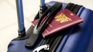 Valise bleue avec passeport et casque audio pour voyage.