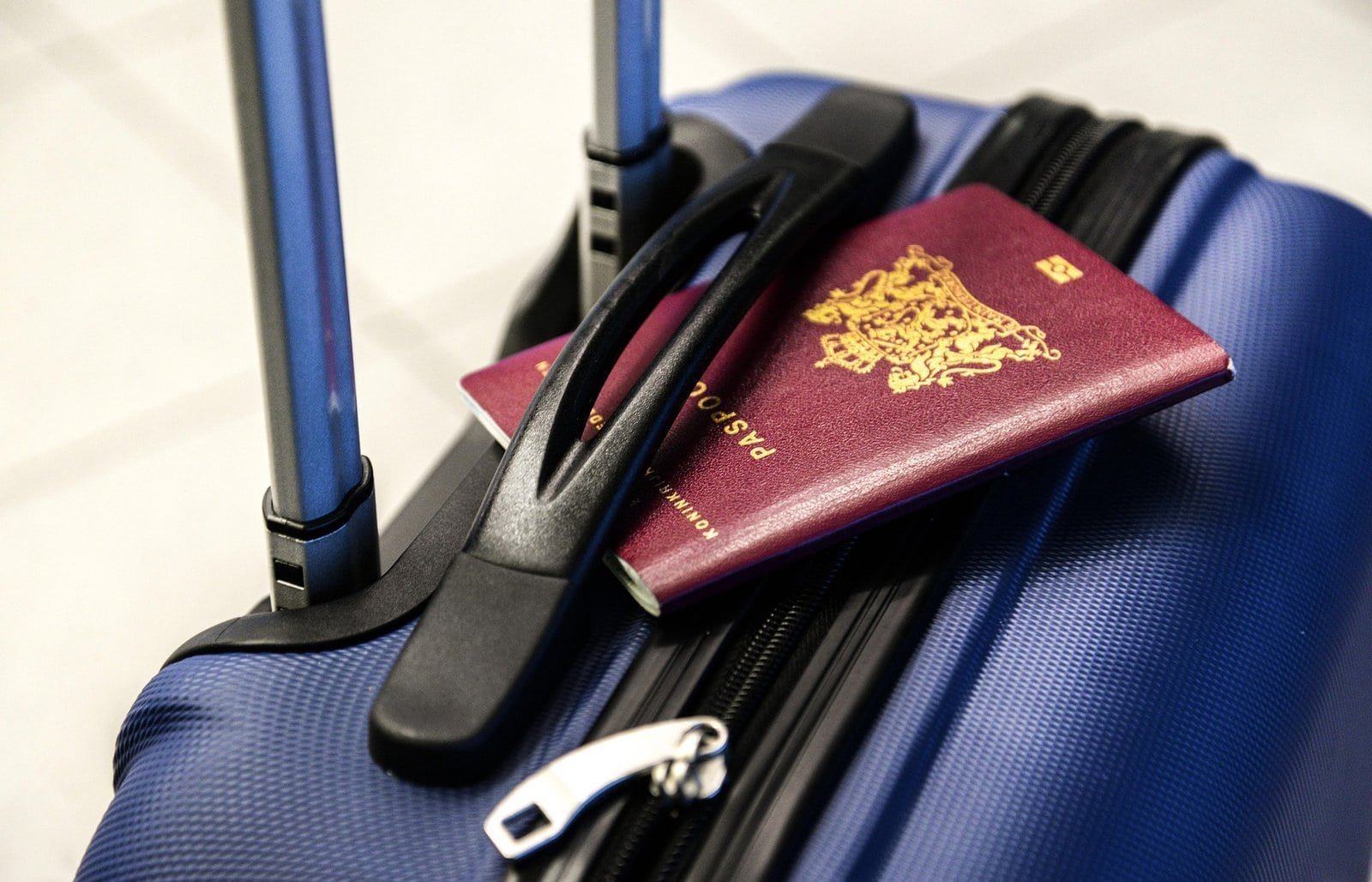 Valise bleue avec passeport et casque audio pour voyage.